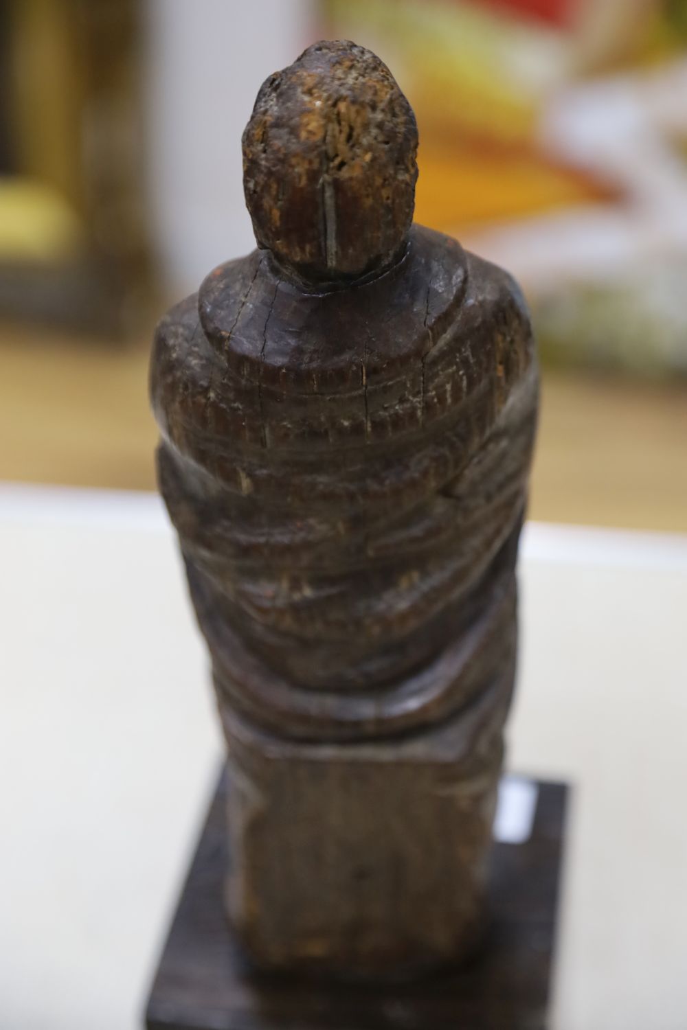 A carving of a saint in prayer, on stand